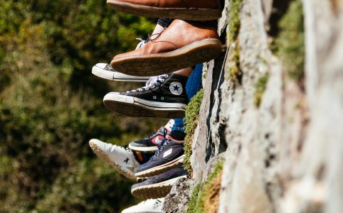 tilt-shift view of feet in sneakers, presumably belonging to people sitting atop a stone wall