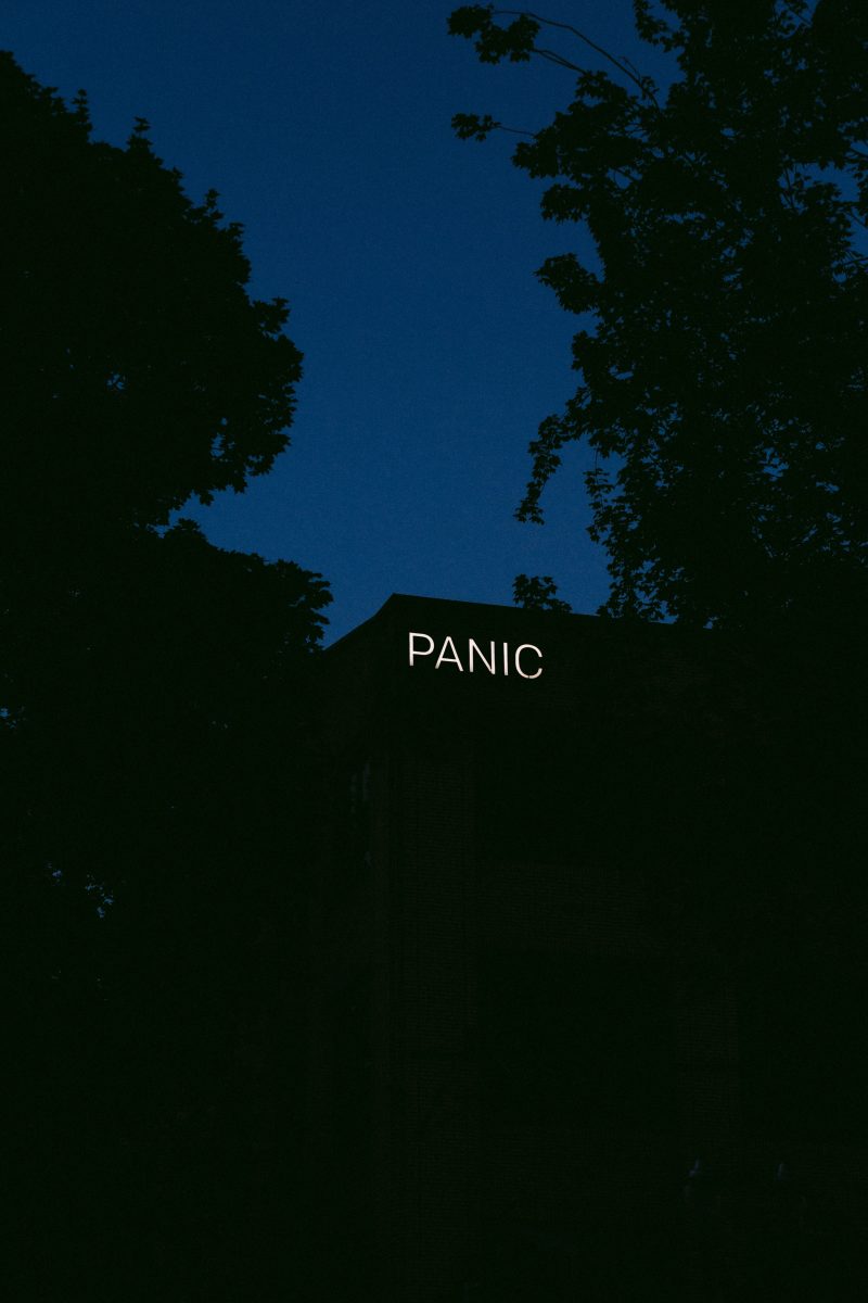 a neon sign reading PANIC on the side of a building in the dark