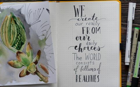 an open sketchbook with a watercolor flower bud on the left page, and the words 'We create our reality from our daily choices; the world consists of bills of realities."