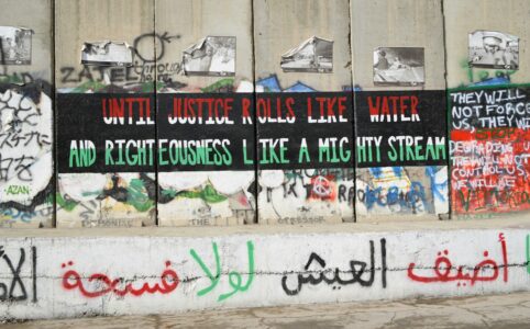 graffiti on a concrete wall in multiple languages, in the colors of Palestine