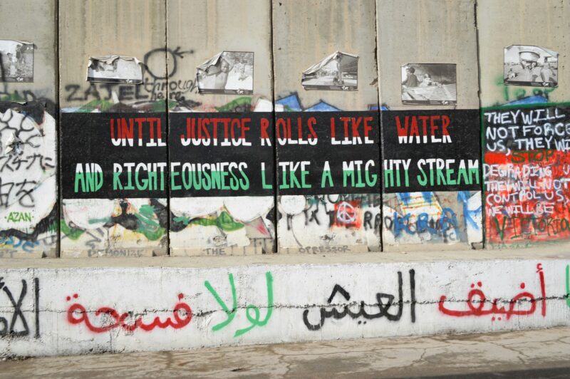 graffiti on a concrete wall in multiple languages, in the colors of Palestine